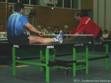 Jindrich Pansky und Milan Orlowsky liegen auf der Tischtennisplatte und spielen Tischtennis